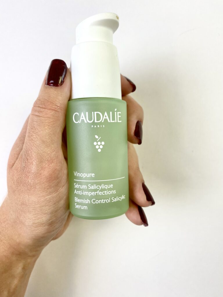 Main qui tient un flacon de sérum anti-imperfections à l'acide salicylique de la marque Caudalie